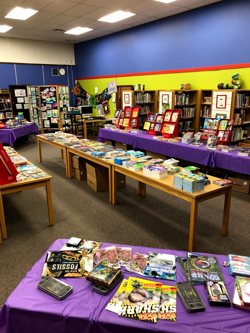 School library ready for book fair with stacks of new books displayed on tables.