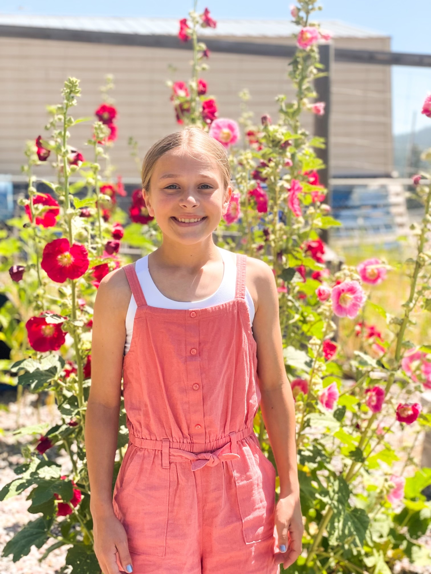 Student standing in front of Hollyhock plants