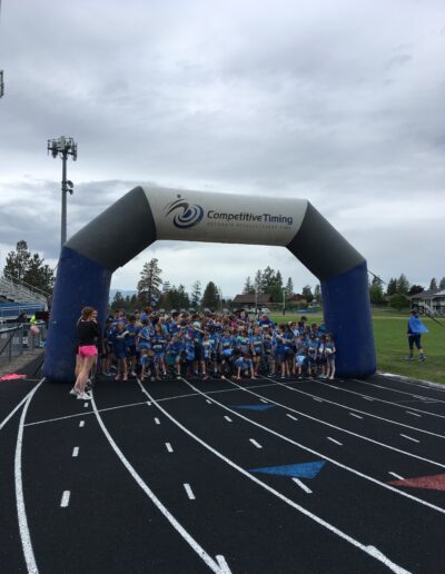 Students dressed in blue crowding at the starting gate to run laps around the track.