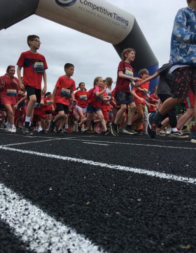 Students dressed in red running on the track.