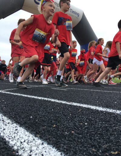 Students dressed in red running on the track.
