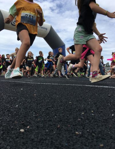 Closeup of students legs and feet as they run laps on the track.