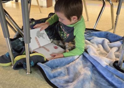 Student wrapped in blanket on the floor while reading.