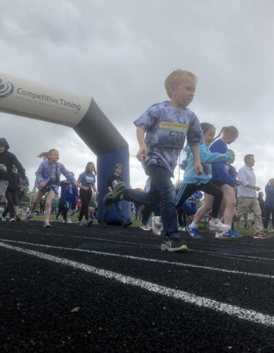 Elementary and middle school students are running out of the starting gate on the track for Bigfork Fun Run 2025.