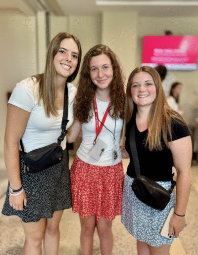 Two NHD students and one representative from the NHD competition stand close together in the lobby of the competition venue.