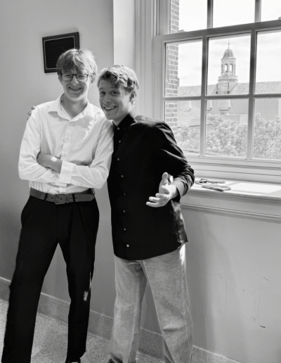 A black and white image of two NHD students in front of a window. Through the window a small tower with domed openings can be seen.