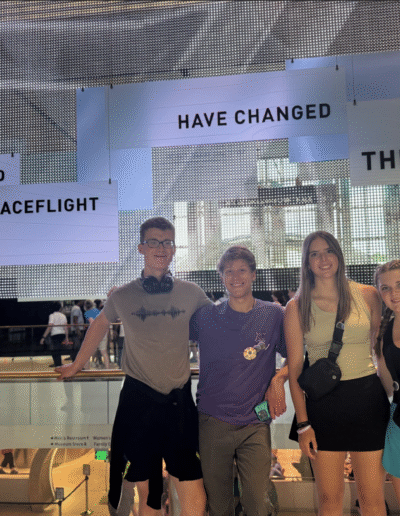 Four NHD students are standing in front of a display which says Aviation and spaceflight have changed the world.