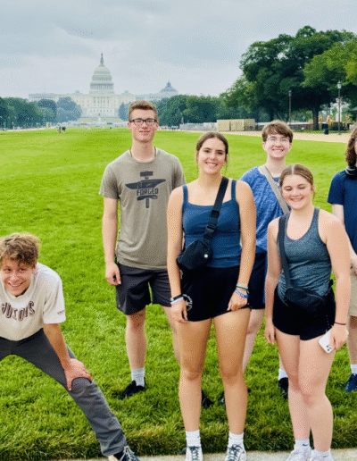 NHD students stand in the sun on a bright green lawn. In the background the U.S. Capitol building can be seen.